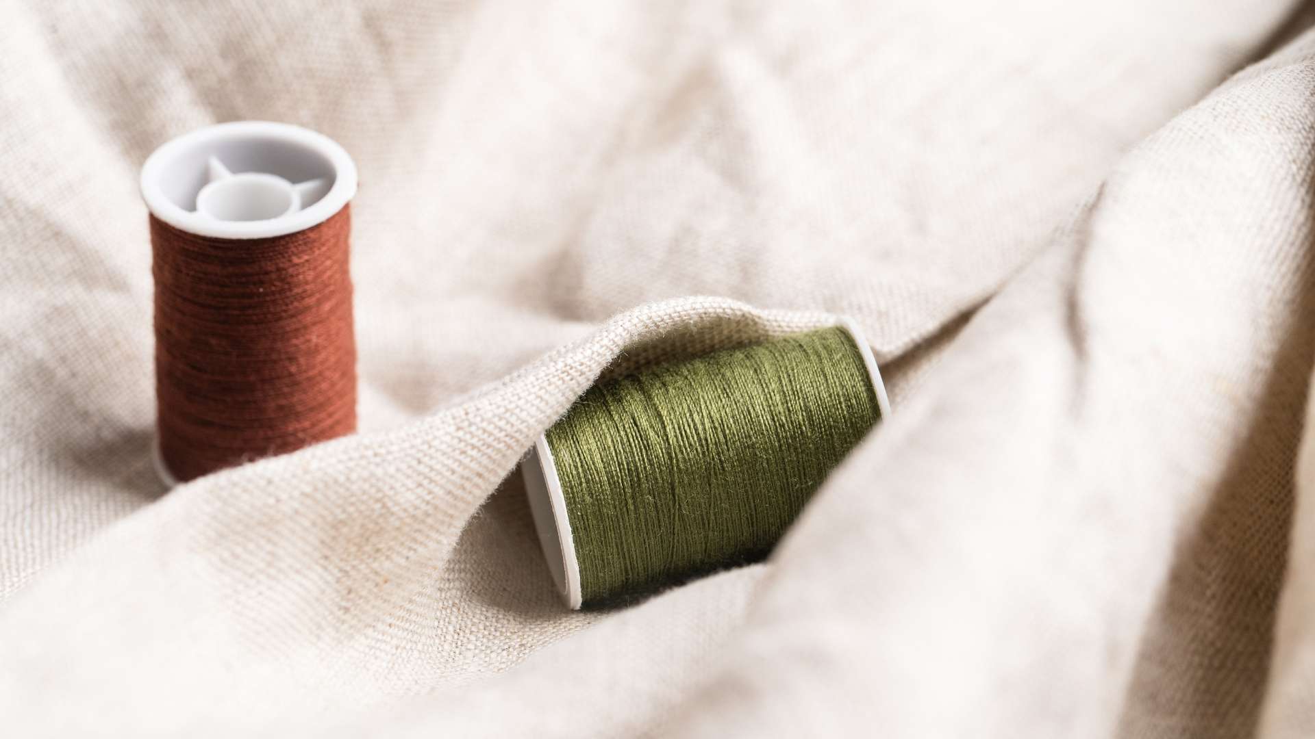 Two threads lying on sustainable material - Kuluki Fashion Marketing.